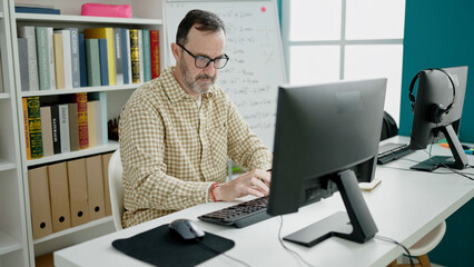 Middle age man teacher using computer working at classroom