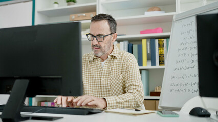 Fototapeta na wymiar Middle age man teacher using computer working at classroom