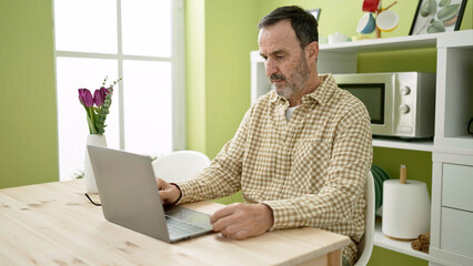 Middle age man using laptop sitting on table at home