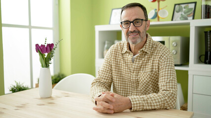 Middle age man smiling confident sitting on table at home