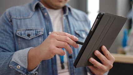 Young chinese man preschool teacher using touchpad standing at kindergarten
