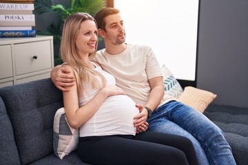 Obraz premium Man and woman couple expecting baby hugging each other at home