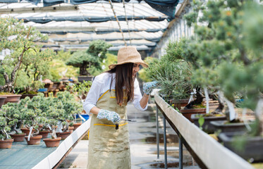 Obraz premium Beautiful woman working in a greenhouse - Gardener taking care of plants and flowers in a botanical garden 
