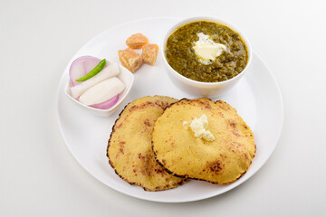 Sarson saag with corn chapati served with white makhan and jaggery in plate isolated on white background