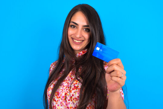 Close up photo of optimistic beautiful brunette woman wearing floral dress over blue background hold card