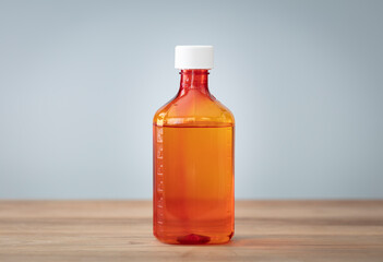 Bottle with liquid medicine. Transparent orange vial with lid on neutral background. Stop your cold...