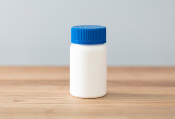 White bottle of medicine on wood surface. Copy space for text or image.
