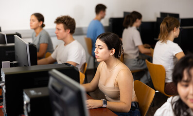 Portrait of interested teen girl during lesson in computer room of school computer class