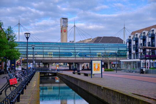 Houten, The Netherlands - April 25 2023. Modern train station in city centre cafe above the canal with town hall tower in the background.