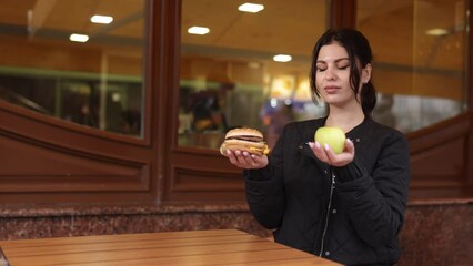 Apple choice, Food priority, Burger dismissal. Woman decides to eat apple instead of indulging in fast food like burger.