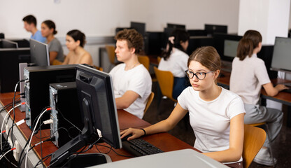 Fototapeta premium Portrait of female schoolgirl at computers in university computer class