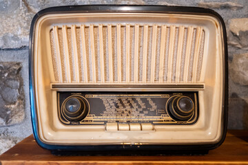 an old radio on a shelf on a stone background with volume, tone and tuning controls, with the name...