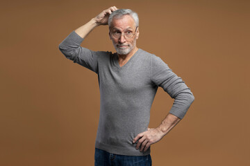 Puzzled doubtful senior man scratches head, thinks about problems, reasoning over solution and ideas