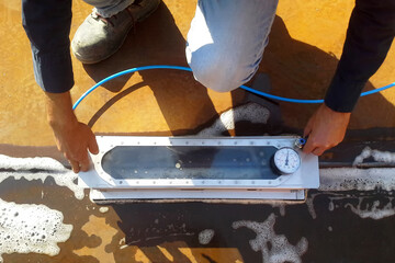 Inspector performs leak test on welds of storage tank with vacuum box device. Leakproofing pressure...