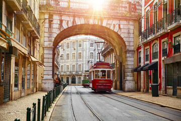 Lisbon, Portugal. Vintage red retro tram on narrow bystreet tramline in Alfama district of old...