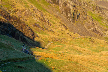 Hikers on Pyg track at sunrise overlooking Crib Goch in Snowdonia. North Wales