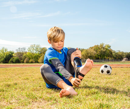 Male youth soccer player has difficulty putting on shin guards or taking them off