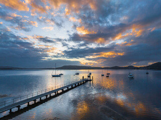 Fototapeta premium Aerial sunrise over the water with low cloud cover, boats and reflections