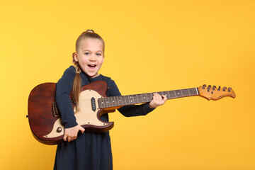Happy girl with electric guitar on yellow background. Space for text