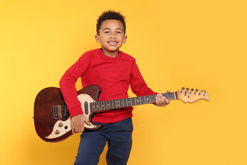 African-American boy with electric guitar on yellow background. Space for text