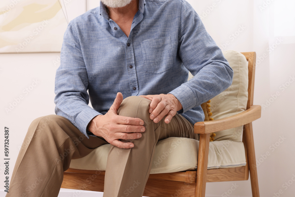 Poster Senior man suffering from pain in his knee at home, closeup. Arthritis symptoms