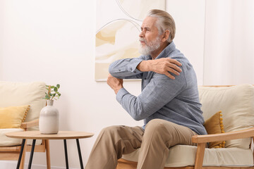 Senior man suffering from pain in his elbow at home. Arthritis symptoms