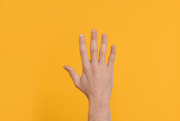 Man giving high five on yellow background, closeup of hand