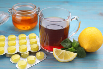 Cold remedies and cough drops on light blue wooden table, closeup