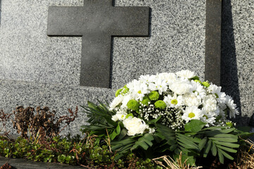 Funeral wreath of flowers near grave outdoors