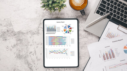 Tablet with charts and reports on office desk workplace. Top view flat lay..