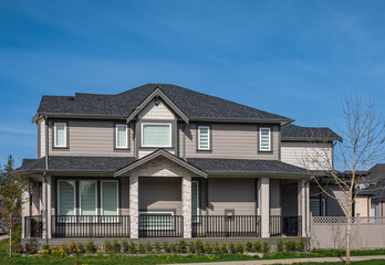 Real Estate Exterior Front House on sunny day. Big custom made luxury house with nicely landscaped front yard in spring