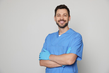 Fototapeta premium Doctor or medical assistant (male nurse) in uniform on light grey background. Space for text