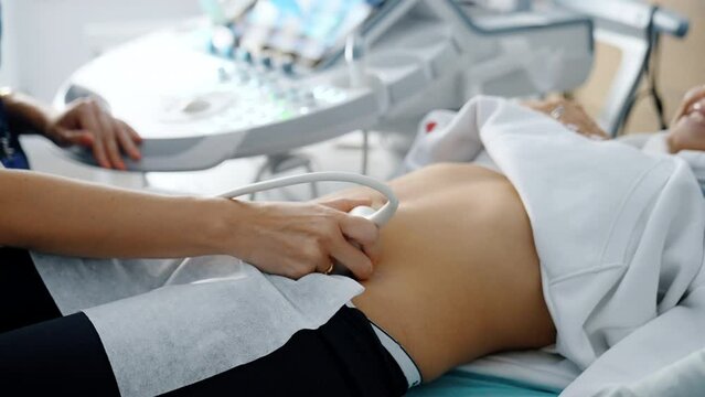 Doctor moving sensor of ultrasound machine by the female belly. Ultrasonic diagnostics on early stages of pregnancy.