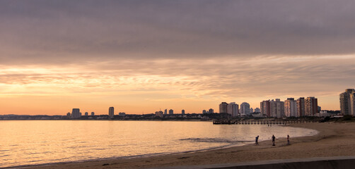 Sunset over Mansa beach in Maldonado bay, with some apartment buildings on the horizon