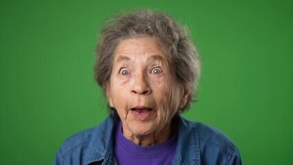 Closeup portrait of thinking, smart puzzled pensive elderly senior old woman with wrinkled skin and grey hair looks around thinks has great idea raised finger isolated green screen background