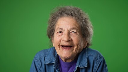 Closeup portrait of toothless elderly senior old woman with wrinkled skin and grey hair getting great happy with success winner isolated on green screen background. Emotions concept