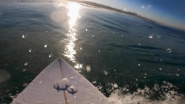 Surfer surfing Wave during huge sunrise at Costa da Caparica beach, Portugal. beautiful sun rays on water. backside mood.