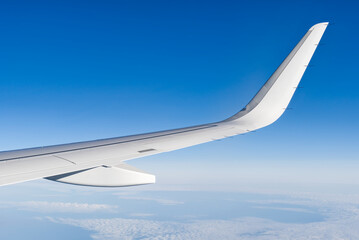 Airplain wing view thrue window in the sky. Clouds and sky as seen through porthole of an aircraft...