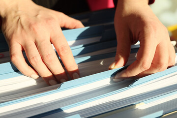 Secretary looks for folder with accounting papers in archive