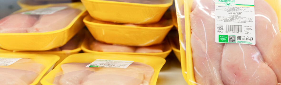 Fresh chicken meat in packages on a shelf in a store. Semi-finished products for fast food preparation. Close-up. Panorama format. Moscow, Russia, 2023-04-10.