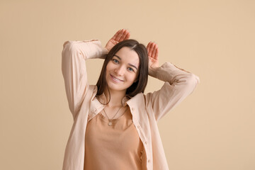 Funny young woman on beige background
