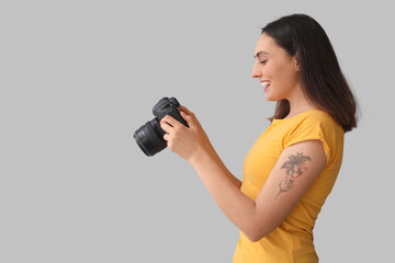 Obraz premium Female photographer with professional camera on grey background