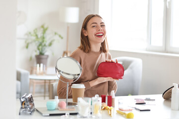 Young woman with red cosmetic bag at home