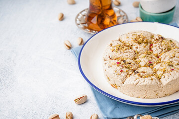 Plate of tasty Tahini halva with pistachios on light background, closeup