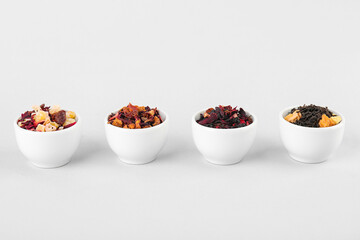 Bowls with different dried fruit tea on white background