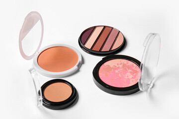 Eyeshadows, blush and makeup powder on light background