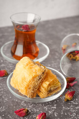 Bowl with tasty baklava on grunge background
