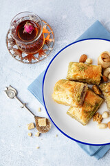 Plate with tasty baklava and glass of Turkish tea on light background, closeup