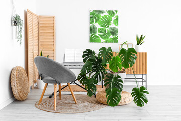 Interior of light room with synthesizer, armchair and Monstera houseplant