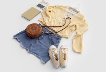 Stylish female clothes with accessories, mobile phone and book on white background